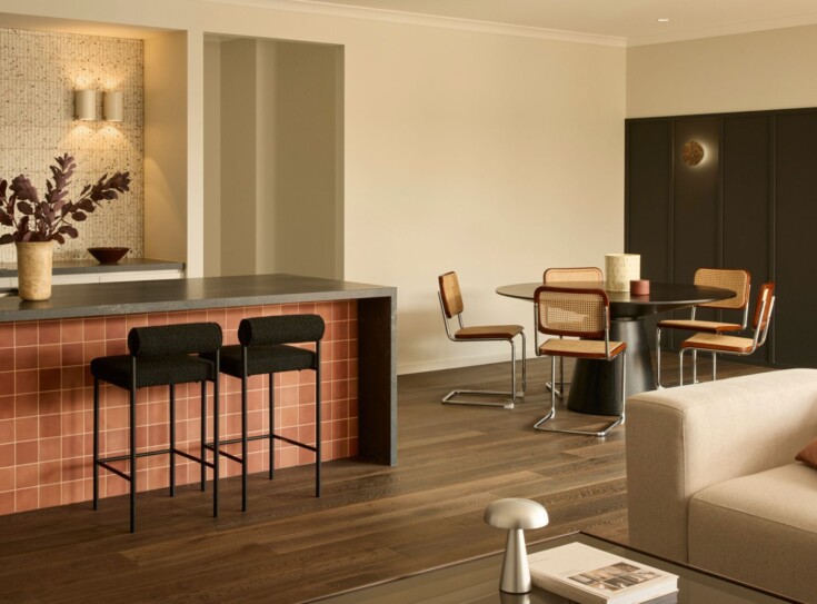 Boutique Homes open-plan kitchen, dining and living space featuring a tiled island bench, timber flooring and a warm, cohesive material palette.