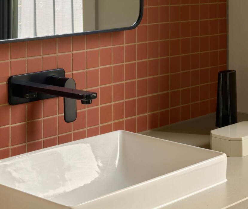 Boutique Homes bathroom vanity featuring a vessel basin, matte black wall-mounted tapware and a warm tiled splashback.