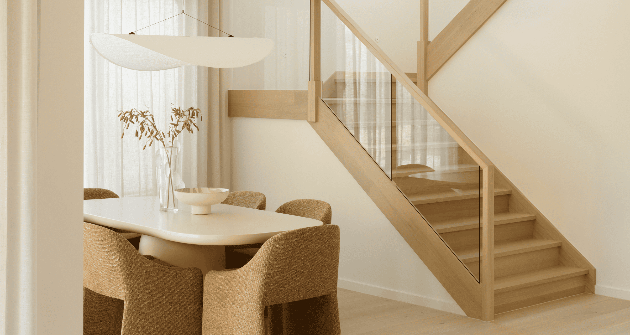 Montpellier 35 dining area with table, chairs and timber staircase with glass balustrade