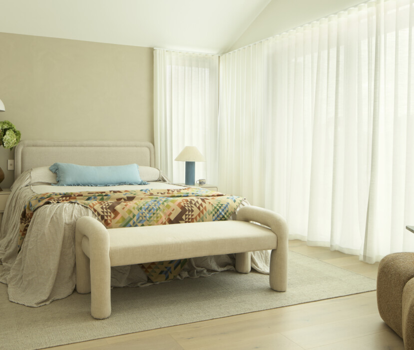 Coastal style bedroom with upholstered bed, neutral tones and sheer curtains