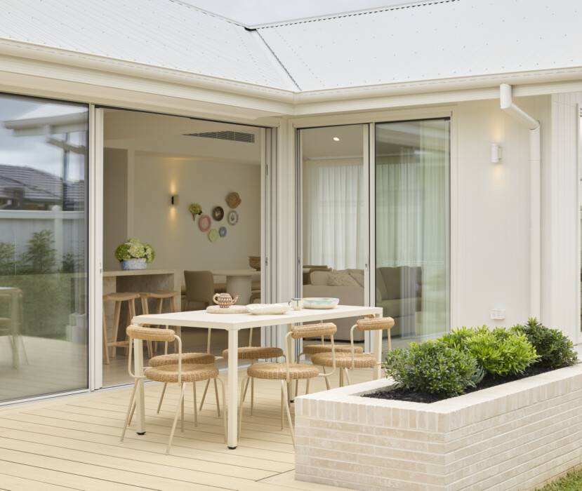 Outdoor alfresco dining area with timber deck, sliding doors and landscaped garden