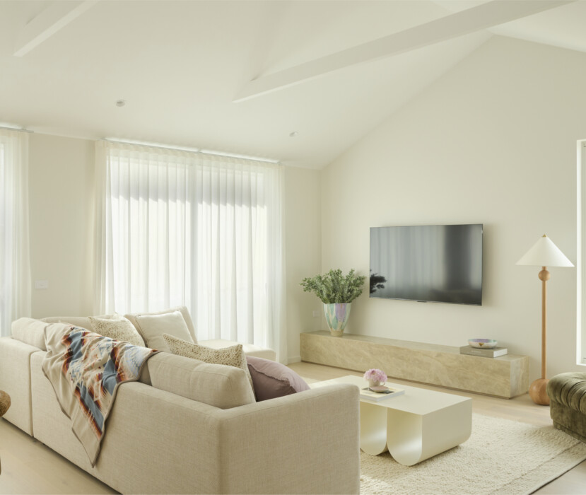 Light-filled living room with neutral sofa, wall-mounted TV and large windows