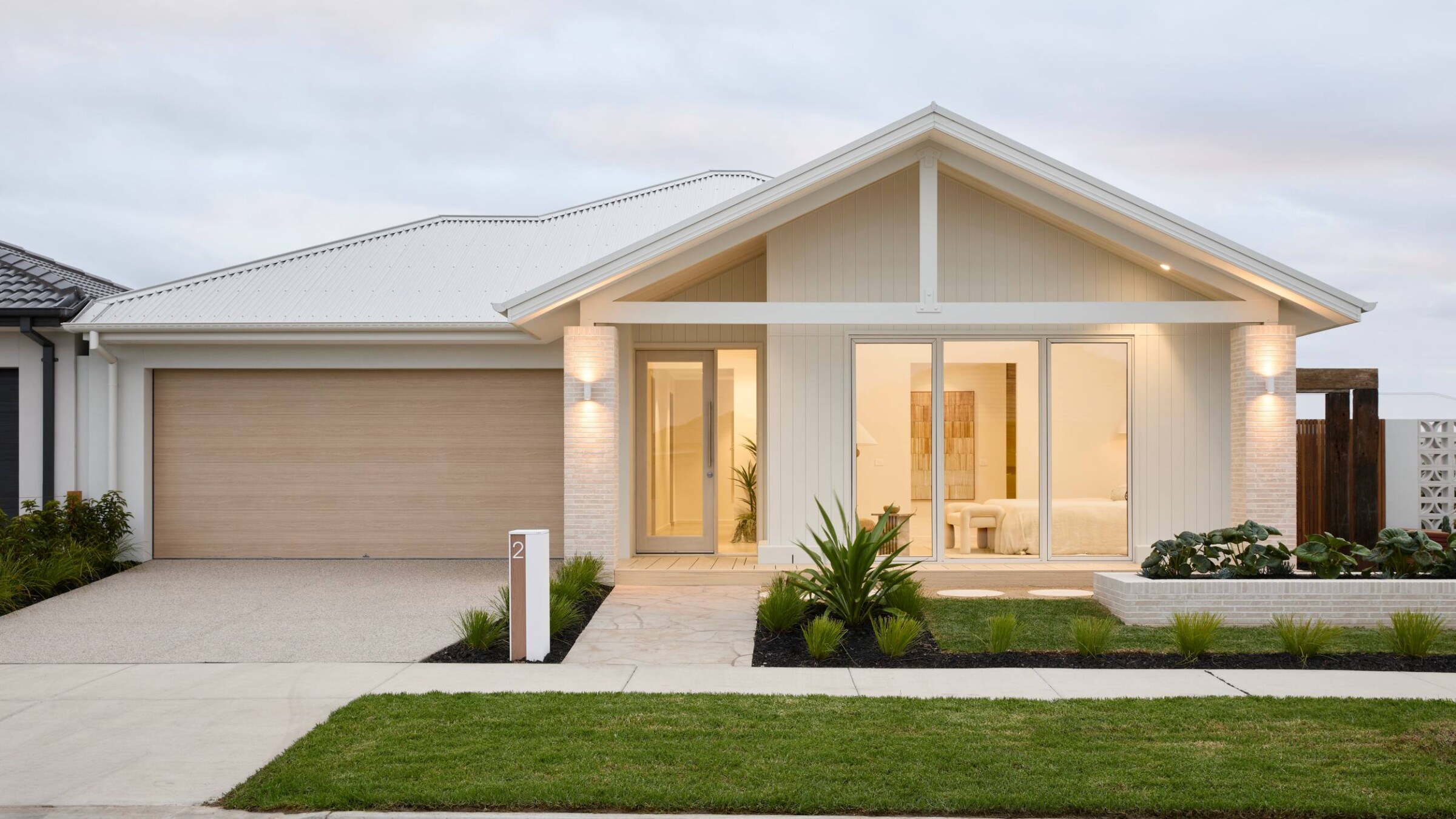 Modern coastal cottage home exterior with double garage and contemporary landscaping
